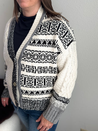 Person wearing a patterned cardigan with a plain background