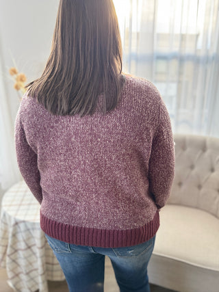 Person wearing a maroon sweater in a room with a couch and window.