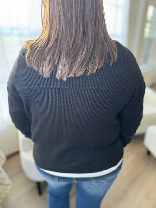 Person wearing a dark blue sweater and blue jeans in a room with white furniture.