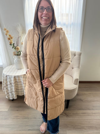 Woman wearing a beige puffer vest in a living room setting