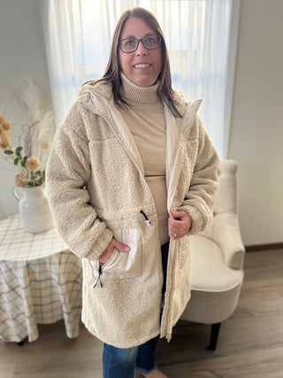 Woman wearing a beige fleece jacket in a home setting