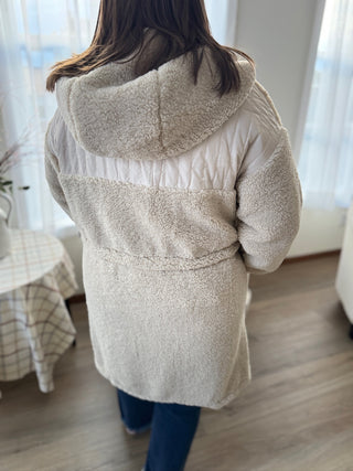 Person wearing a beige fleece-lined jacket indoors