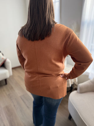 Person wearing a brown sweater in a living room setting