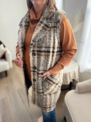Person wearing a patterned vest over a brown sweater in a home setting