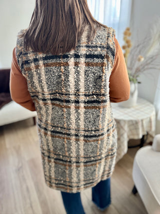 Person wearing a plaid vest in a room with furniture and decor.
