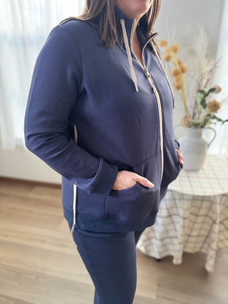 Person wearing a navy blue tracksuit in a room with a table and plants.