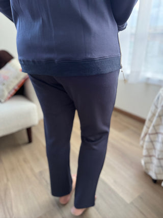 Person wearing navy blue pants in a room with a couch and window.