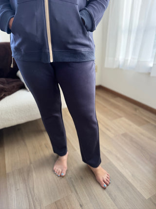 Person wearing a navy blue tracksuit standing on a wooden floor.