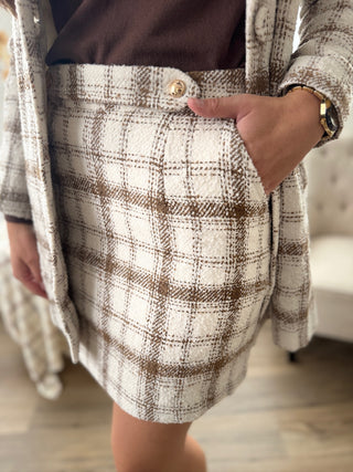 Person wearing a plaid skirt with a neutral background