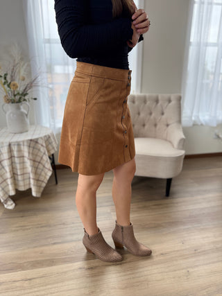 Person wearing a brown skirt and dark top in a room with a couch and table.