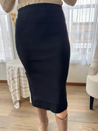 Person wearing a black pencil skirt in a room with curtains and furniture.