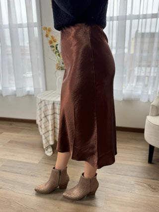 Person wearing a brown skirt and brown shoes indoors.