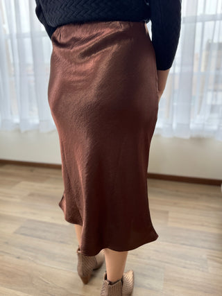 Person wearing a brown skirt indoors with a neutral background