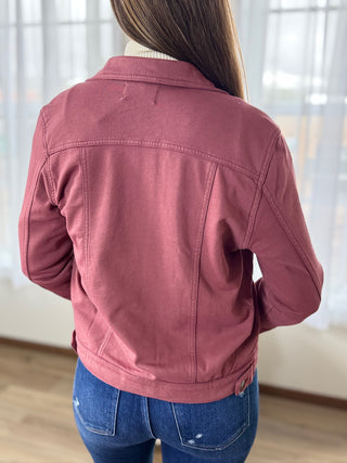 Person wearing a pink jacket and blue jeans indoors