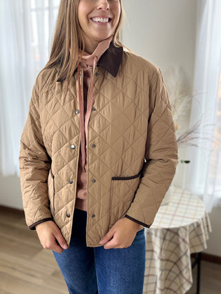 Person wearing a quilted beige jacket indoors