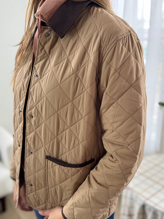 Quilted beige jacket worn by a person indoors