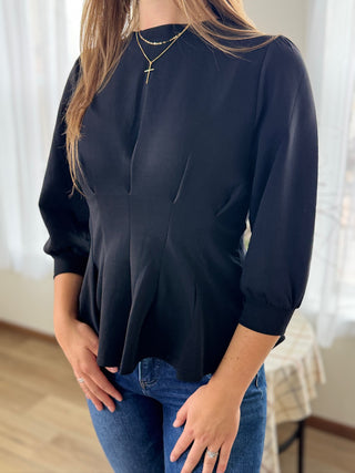 Person wearing a black blouse and blue jeans indoors