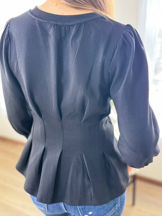 Blue peplum top worn by a person with a blurred background