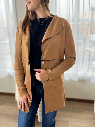 Woman wearing a brown coat indoors with a blurred background