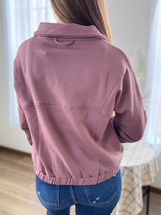 Person wearing a pink jacket and blue jeans indoors.