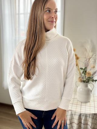 Woman wearing a white sweater in a home setting