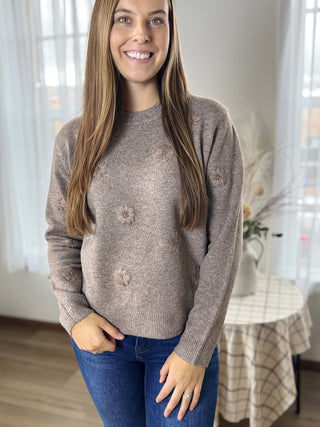 Woman wearing a brown sweater with floral patterns indoors