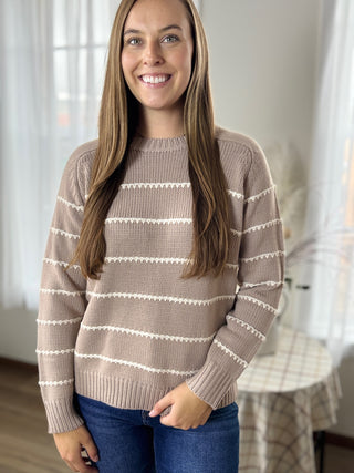 Woman wearing a striped sweater in a neutral indoor setting