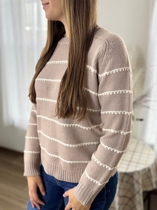 Woman wearing a beige sweater with white stripes indoors