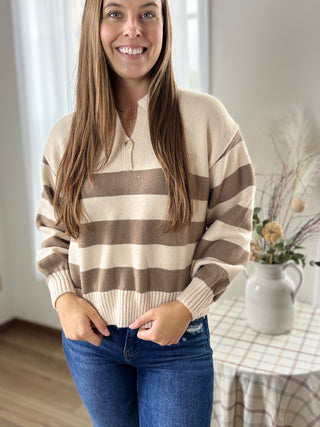 Woman wearing a beige and brown striped sweater in a home setting