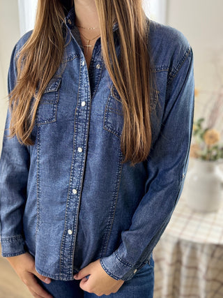 Person wearing a blue denim shirt with a blurred background