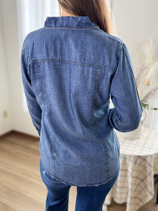 Person wearing a blue denim shirt in an indoor setting