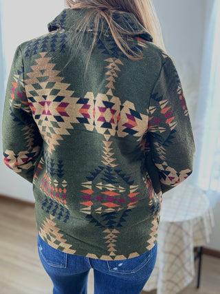 Person wearing a green patterned shirt with a blurred background