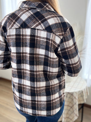 Person wearing a plaid shirt with a neutral background
