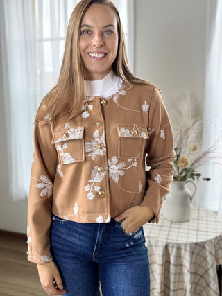 Woman wearing a brown floral embroidered jacket indoors