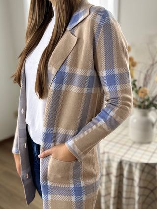 Person wearing a beige and blue plaid coat indoors