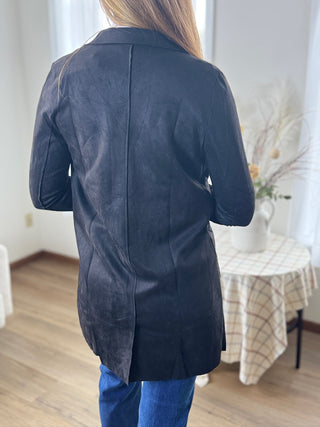 Person wearing a dark blue coat in a room with a table and chairs.