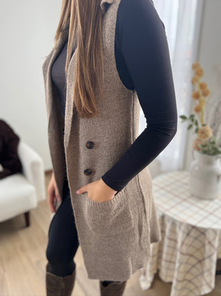 Person wearing a long brown knitted vest indoors