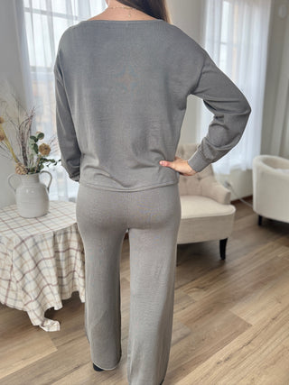 Person wearing a gray sweatshirt and pants in a living room setting