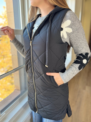 Photo of a woman in a black quilted puffer vest.