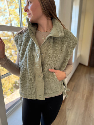 Photo of a woman in a sage green sherpa vest.