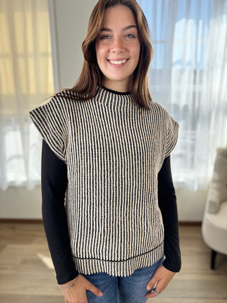 Woman wearing a black and white striped sleeveless top with a plain background