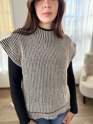 Woman wearing a black and white striped sweater with a plain background