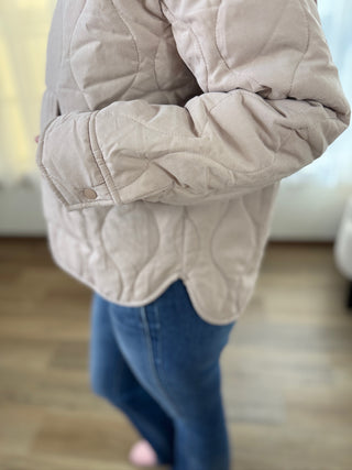 Beige quilted jacket worn by a person with a blurred background