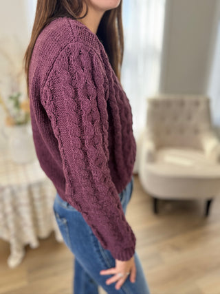 Person wearing a purple knitted sweater in an indoor setting