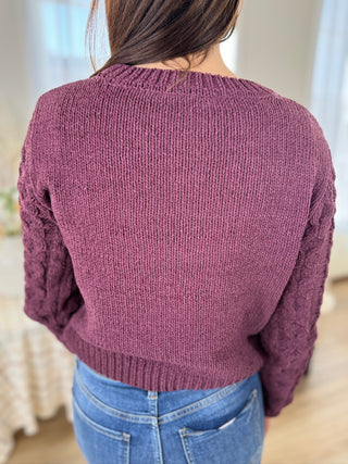 Person wearing a purple sweater and blue jeans indoors