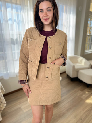 Woman wearing a beige jacket and skirt in a living room setting