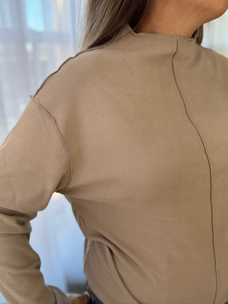 Beige long-sleeve top worn by a person with a blurred background