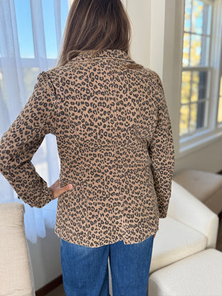 Person wearing a leopard print shirt in a room with a window and sofa.
