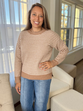 Woman wearing a checkered sweater and blue jeans standing in a living room.