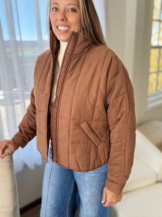 Woman wearing a brown quilted jacket indoors
